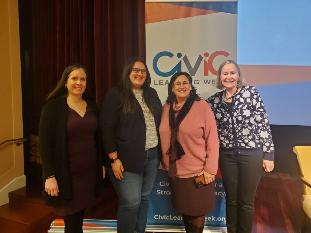 Four women standing in front of Civic Learning Week banner
